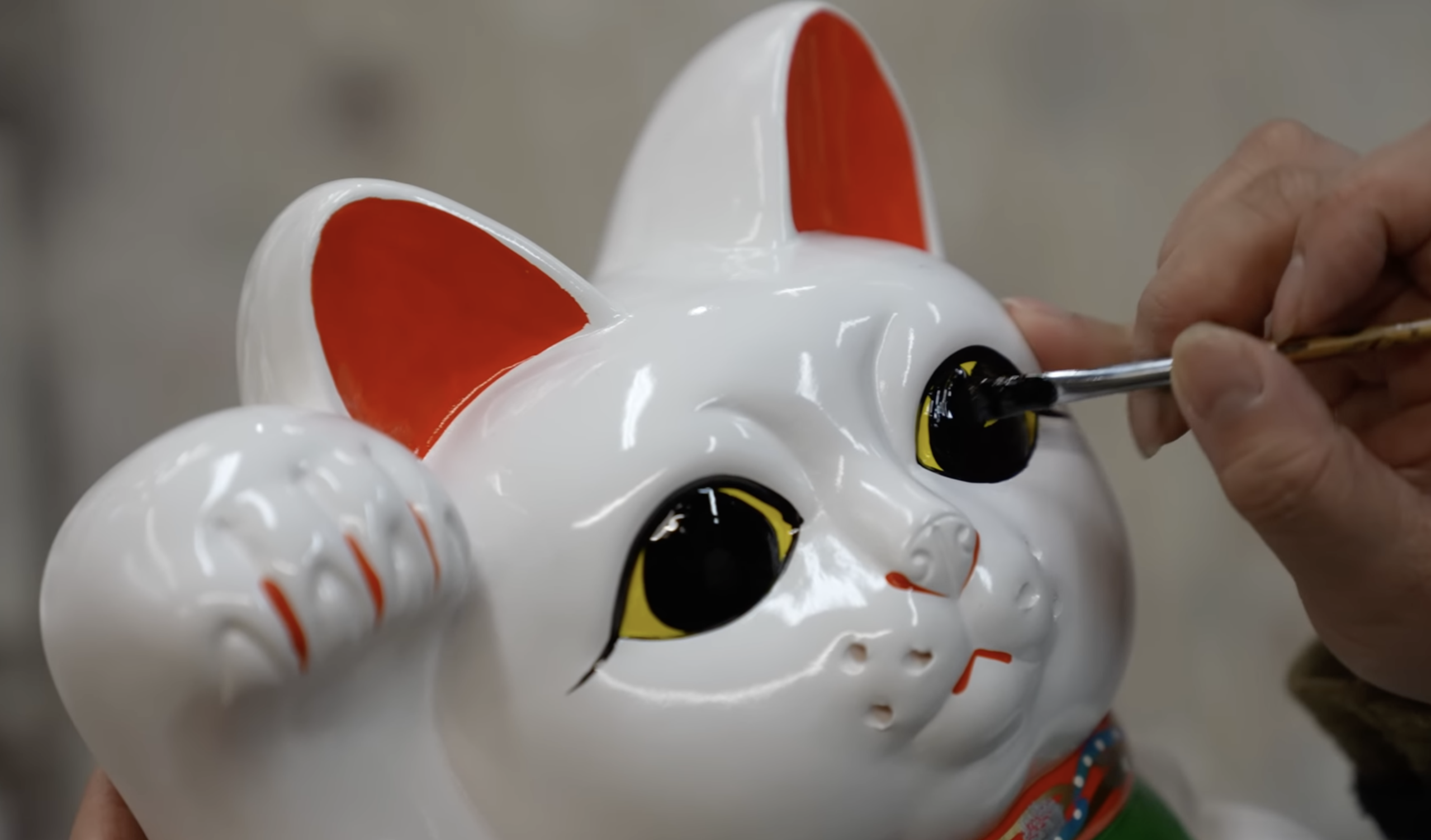 craftsman carefully painting the eyes of a Maneki Neko figurine